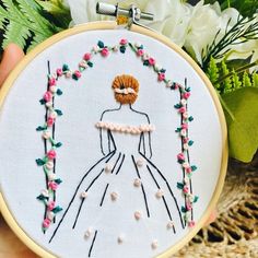 a hand embroidered picture of a woman in a wedding dress with flowers on the side