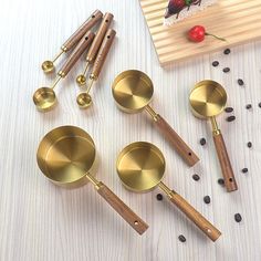 five brass measuring spoons and four wooden spatulas on a white tablecloth