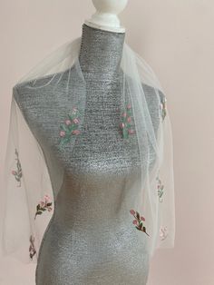 a mannequin wearing a silver dress with pink flowers on it's chest