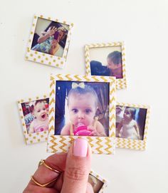 a person holding a small photo frame in front of four pictures on the wall with their fingers