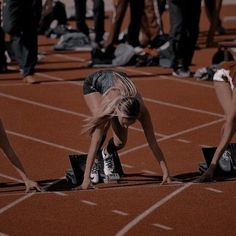 several people standing on a track with their feet in the ground and one person bending over