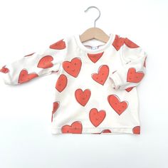 Super Cute fun heart printed t-shirt.  Available in a choice of long or short sleeves from sizes 0-3 months up to age 5-6years Our long sleeved T shirts are made of our usual super soft light fabric and are finished with cute little cuffs and a double stitched hem; perfect for layering under rompers or mix and matching with our leggings. Pattern placement may be different to that shown. Coordinating leggings, romper, hats and bibs also available. Sizing runs true to size with a relaxed fit.  See Photos for Sizing. We understand every little person is unique so if you would like to request custom sizing please just pop a note the 'add an optional note to seller' box.  Most items are made to order so please allow up to 7 days for them to be shipped.  If you need an order in a hurry get in to Red Long Sleeve T-shirt With Cartoon Print, Fun Red Tops For Playwear, Fun Red Top For Playwear, White Graphic Tee With Heart Print, White Long Sleeve Tops With Heart Print, White Long Sleeve Top With Heart Print, Red Long Sleeve Printed T-shirt, Red Printed Long Sleeve T-shirt, Red Long-sleeve T-shirt With Cartoon Print