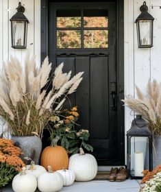 a front door with pumpkins and flowers on the steps, next to a lantern