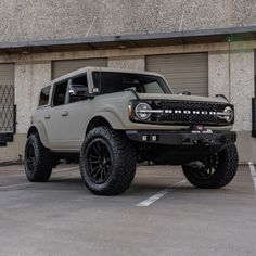 an off - road truck parked in front of a building with garage doors and windows