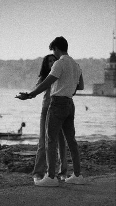 black and white photograph of two people standing near water