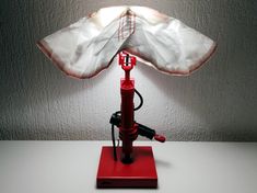 a red lamp with an umbrella shade on it's head sitting on a table