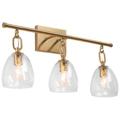 three light bathroom fixture with clear glass shades and gold metal fittings on the wall