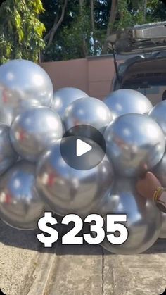 a man is holding some silver balls in front of a car and the words $ 23 95 on it