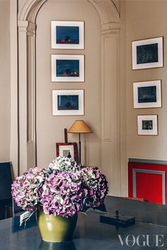 a vase filled with purple flowers sitting on top of a table next to a lamp