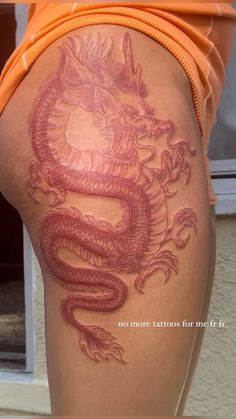 a woman's thigh with a dragon tattoo on the side and an orange shirt