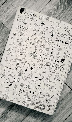 a notebook with doodles on it sitting on top of a wooden floor