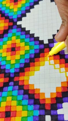 a person is drawing with colored pencils on a piece of paper that has been made out of legos