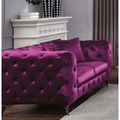 a purple couch sitting in front of a white fireplace