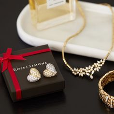 two pieces of jewelry sitting on top of a table next to a box with a red ribbon