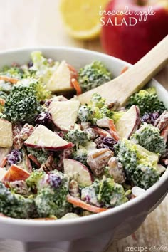 a salad with broccoli, apples and cranberries in a white bowl