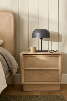 a nightstand with a lamp on top of it next to a bed and a rug