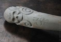 a white carved object with writing on it's face and eyes, sitting on a table