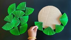 someone is making green paper fan shapes out of cardboard and some other crafting supplies