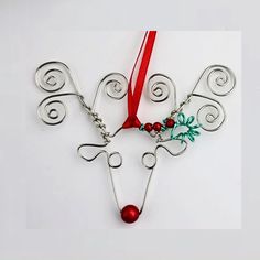 a reindeer ornament hanging from a red ribbon on a white surface with ornaments attached to it