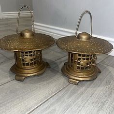 two brass lanterns sitting on top of a wooden floor