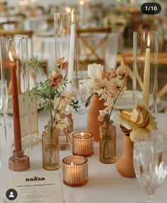 there are many vases with flowers and candles on the table at this wedding reception