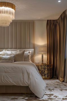 a large bed sitting under a chandelier in a bedroom next to a window