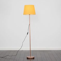 a floor lamp with a yellow shade on the top and an electric cord plugged into it