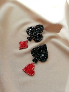 three black and red sequins with hearts on them sitting on a white cloth