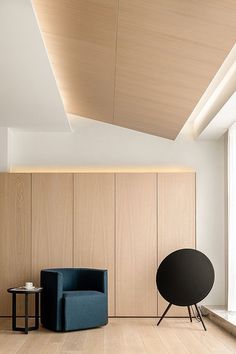 a living room with wooden paneling and blue chair next to a black round table