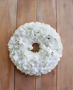 a wreath with white flowers hanging on a wooden wall