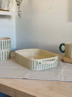 three ceramic dishes sitting on top of a wooden table next to a potted plant