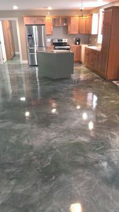 an empty kitchen and living room with marble flooring in the foreground, stainless steel appliances on the far wall