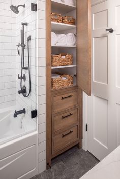 an open cabinet in a bathroom with towels on the shelves and bathtub next to it