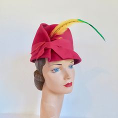 "I believe this hat is from the late 1950's to the early 60's. Made in a vibrant rich magenta pink wool felt. High crown and small brim. Architectural folds on the side brim and crown. Trimmed on the side front with a bright multicolor parrot feather. Magenta grosgrain ribbon trim around the lower crown. Interior crown is also trimmed with magenta grosgrain. Label:  Valerie Modes Condition:  Excellent.  Looks barely worn if at all. Size/Measurements: crown height-  4.75\" brim diameter-  8.75\" Red Fitted Vintage Top Hat, Red Vintage Mini Hats With Curved Brim, Vintage Red Adjustable Mini Hats, Red Adjustable Vintage Mini Hats, Red Retro Party Hat, Retro Red Party Hat, Retro Pink Wide Brim Hat, Red Vintage Mini Hats For Kentucky Derby, Vintage Red Mini Hat For Kentucky Derby