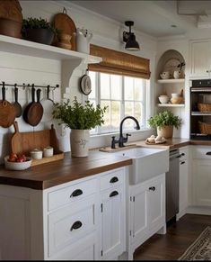 a kitchen filled with lots of white cabinets and wooden counter tops next to a window