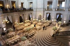 a large room filled with lots of tables covered in white flowers and centerpieces