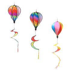 three hot air balloons flying in the sky with streamers attached to them, one is rainbow