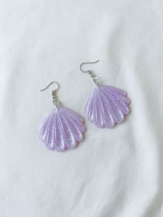 a pair of purple seashell earrings on a white background