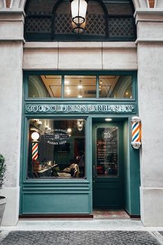 the front entrance of a barber shop with green doors