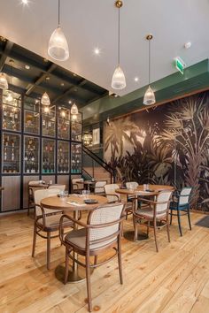 an empty restaurant with wooden tables and chairs in front of a large wallpapered mural