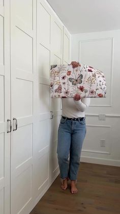 a woman standing in front of white closets holding up a jacket over her head