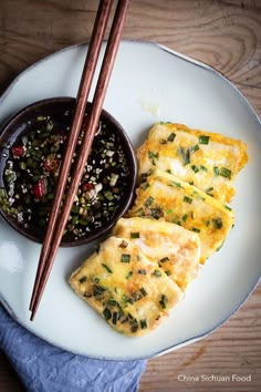 two pieces of omelette on a plate with chopsticks next to it