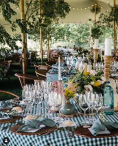 a table set with wine glasses and place settings for an outdoor dinner or party event