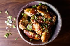 chicken wings with sesame seeds and seasoning in a bowl on a wooden table top