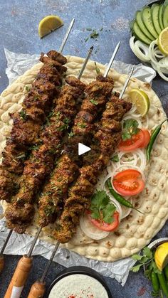 several skewers of meat and vegetables on a platter with dipping sauces