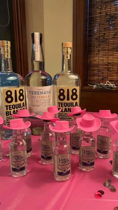 several bottles of gin on a table with pink plates and spoons next to them