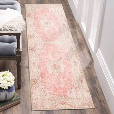 a large rug is on the floor next to a chair and vase with flowers in it