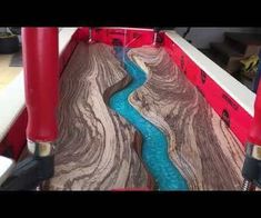 a river flowing through a wooden floor next to red pipes