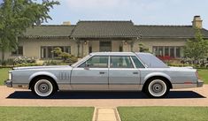 an old car parked in front of a house with a large driveway and grass area