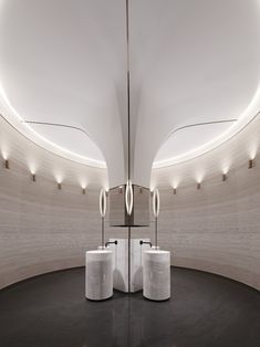 two white pedestals are in the middle of a circular room with mirrors and lights